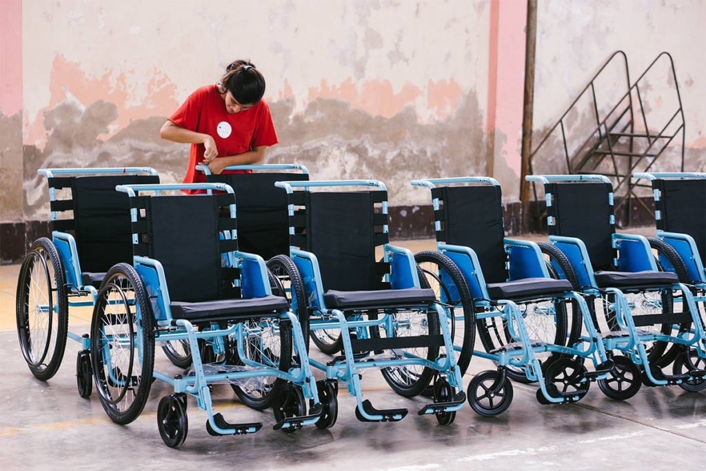 A volunteer prepares a row of new wheelchairs for delivery.