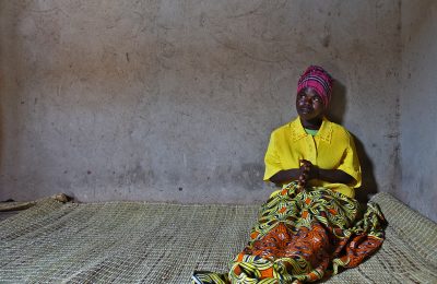 A woman with a disability in Rwanda, confined to a cramped, dark room.