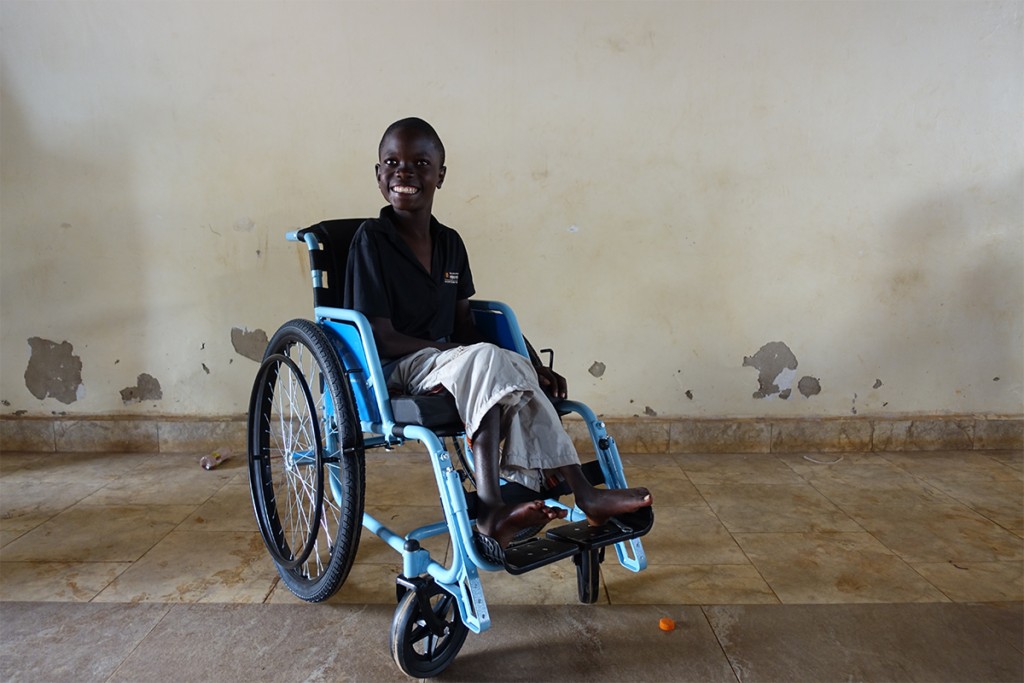 A smiling boy in a wheelchair in Uganda.