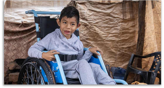 A young boy in Brazil smiles as he sits in his new blue wheelchair.