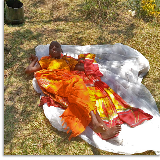 A boy named Emmanuel in Kenya lies on a sheet on the ground.