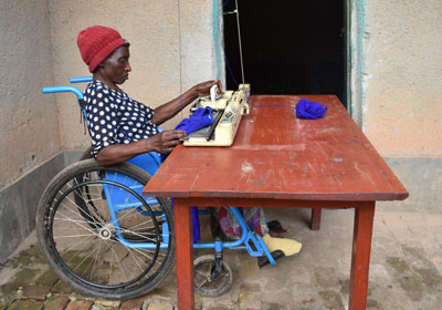 A woman in a wheelchair in Rwanda weaving fabric to make a living.