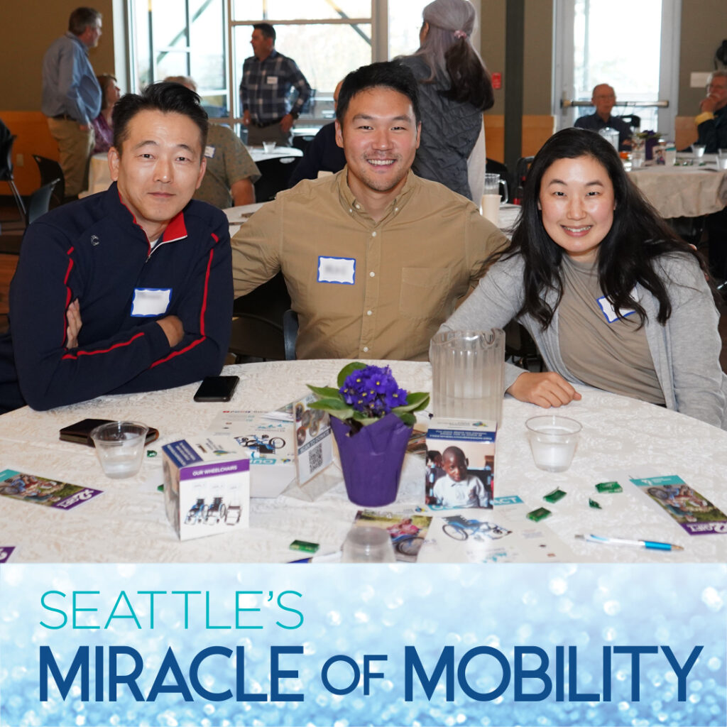 Two men and a woman seated around a table at the 2022 Seattle Miracle of Mobility event.