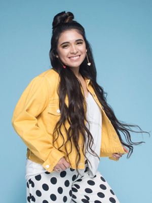 Headshot of singer Courtnie Ramirez in a yellow jacket.