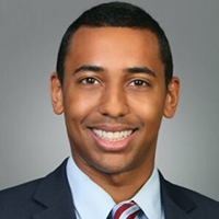 A headshot of a smiling man in a suit and tie.