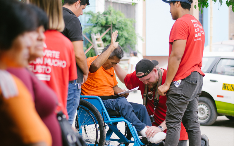 A man in a wheelchair receives prayer from a church team.
